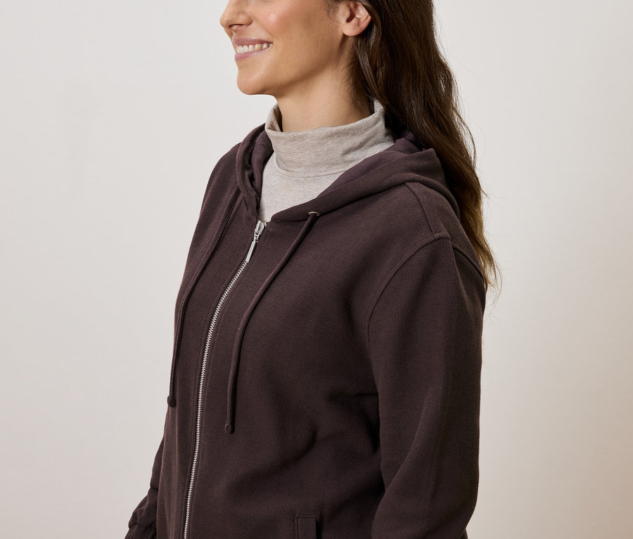 Frau mit braunem Kapuzenpullover mit Reißverschluss und Rollkragen.