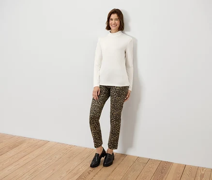 Frau posiert in einem cremefarbenen Langarmshirt und einer Hose mit Animal-Print.