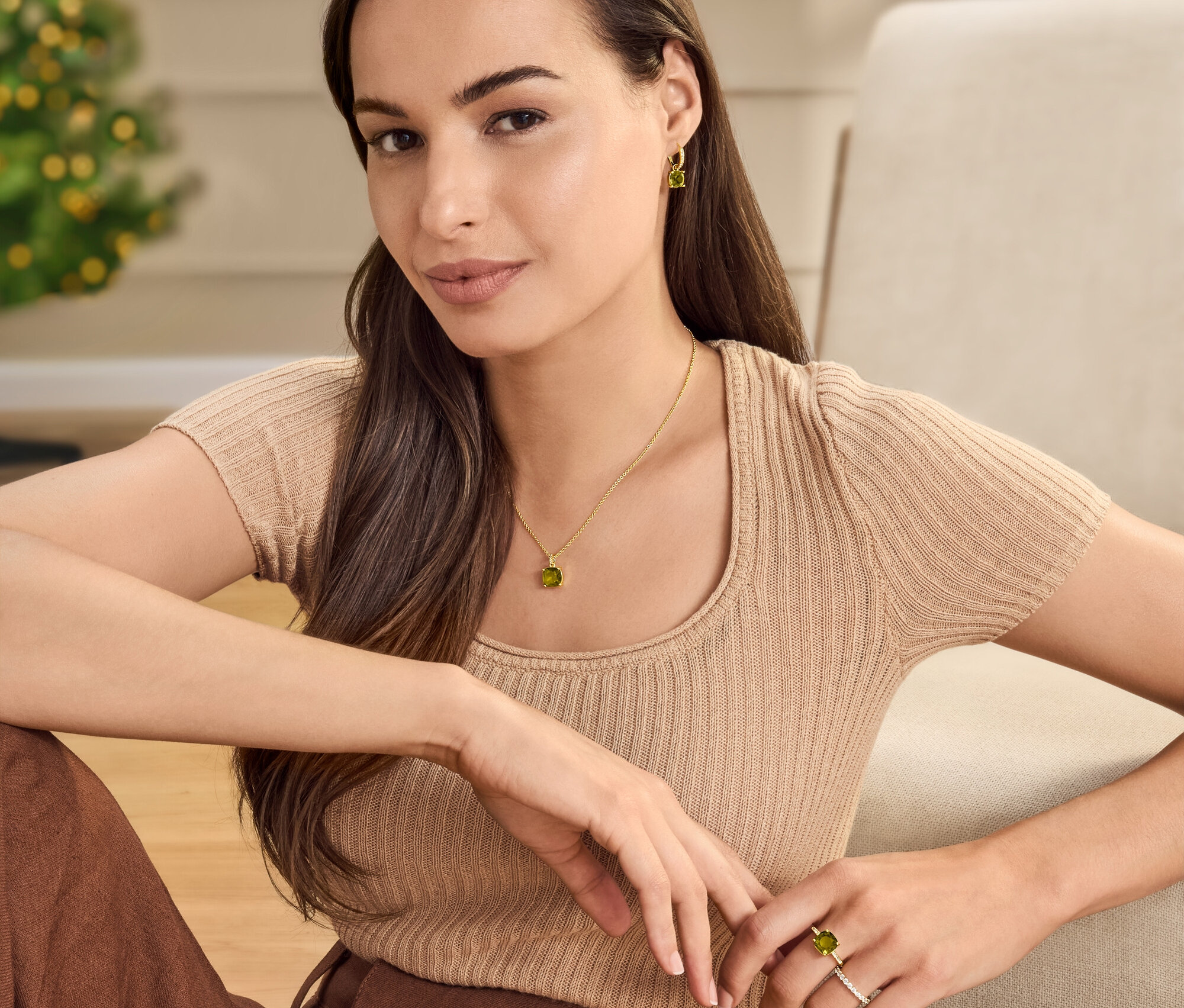 Frau sitzt mit Kette, Creolen und Ring mit grün-braunem Glaskristallstein. Sie trägt zusätzlich einen 925 Silber Ring »Memory«, vergoldet.