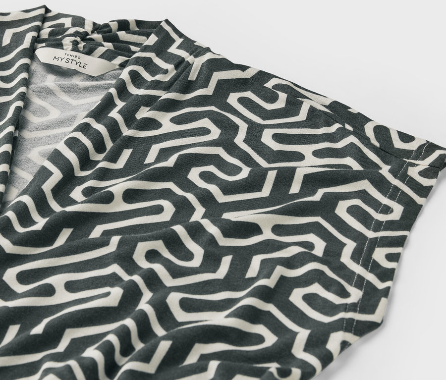 Detailansicht eines grünen Blusenshirts mit V-Ausschnitt und Muster.