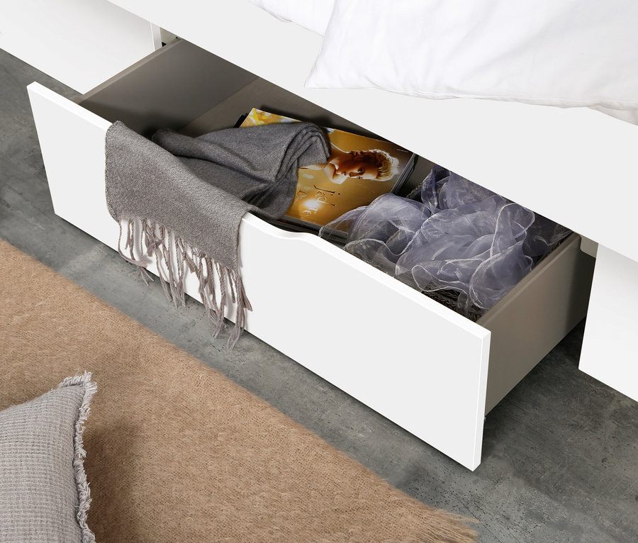 Detailansicht eines weißen Bettes mit offener Schublade, gefüllt mit Kleidung und Accessoires. Rauch Bett »Aditio Beds«, 120 cm mit Polsterkopfteil.