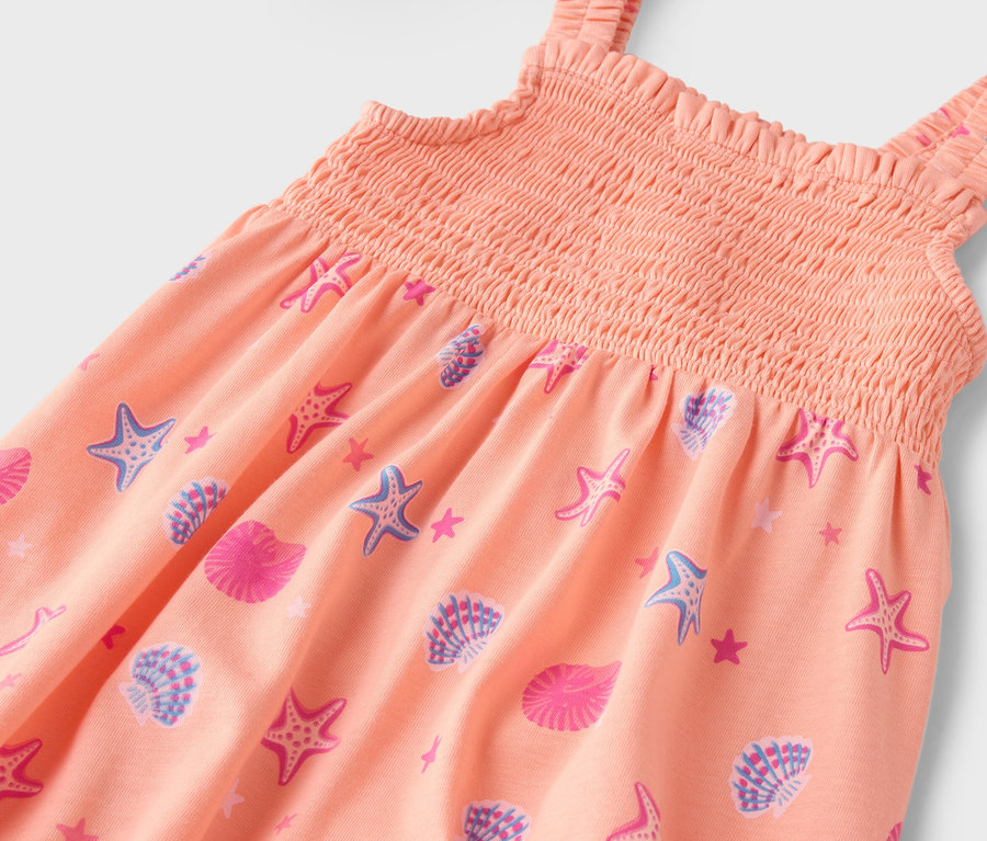 Nahaufnahme eines orangefarbenen Kleides mit Seestern- und Muschelmuster.