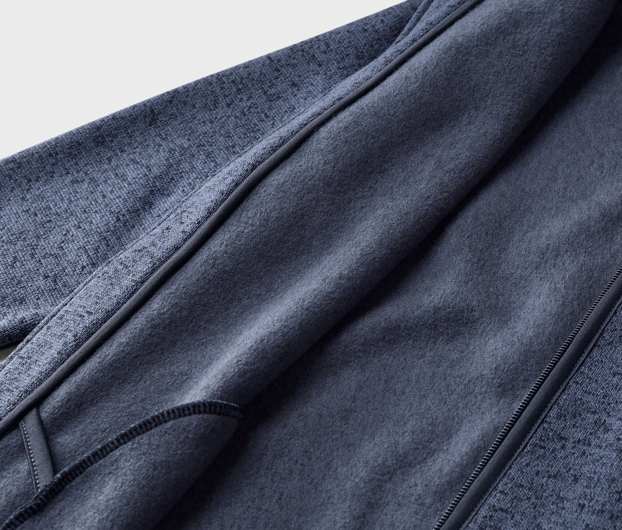 Nahaufnahme einer dunkelblauen Fleecejacke, teilweise geöffnet, um das weiche, einfarbig blaue Innenfutter und den strukturierten Oberstoff zu zeigen.