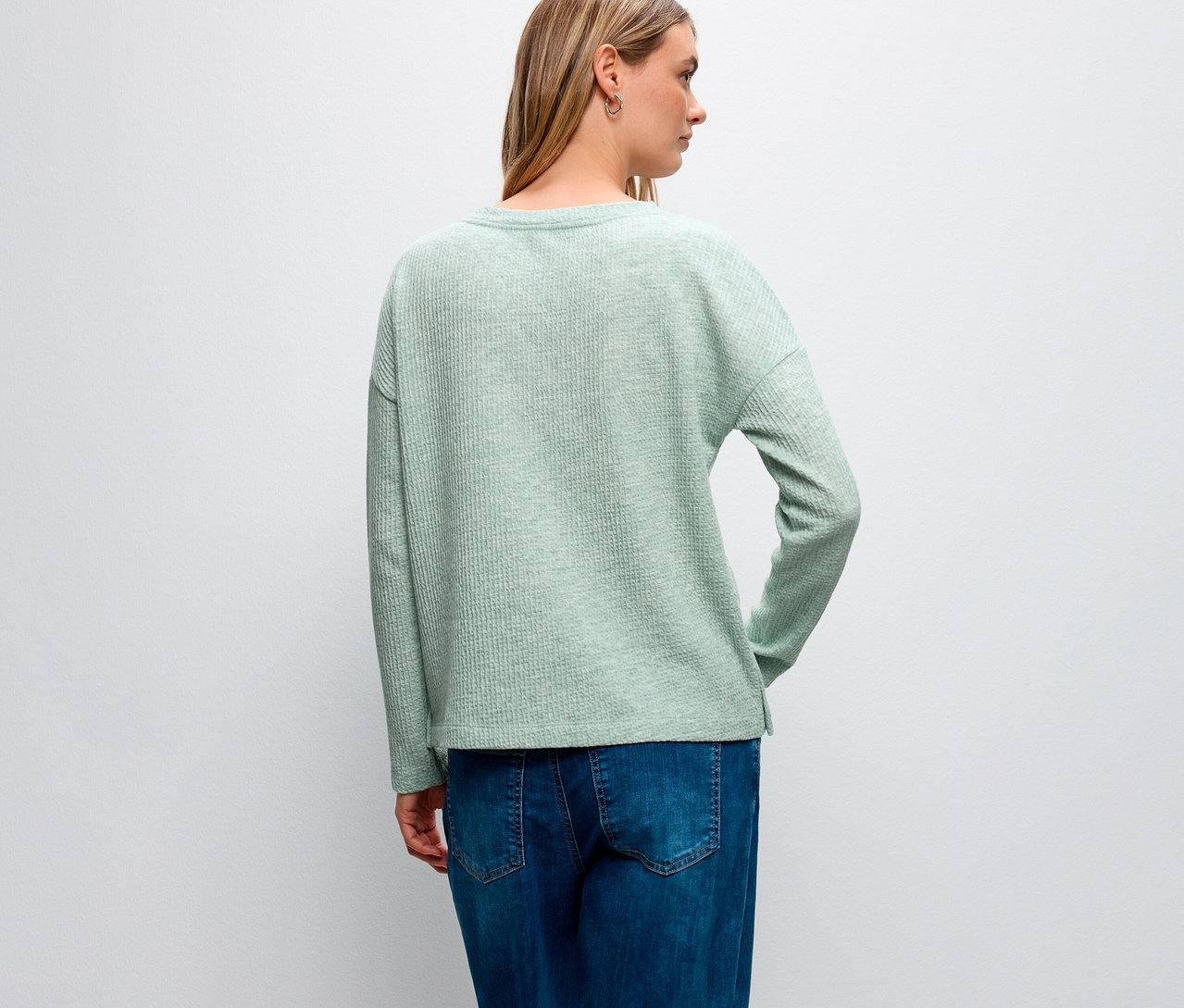 Rückansicht einer Frau mit blonden Haaren, die ein Street One Shirt mit Struktur und blaue Jeans trägt.