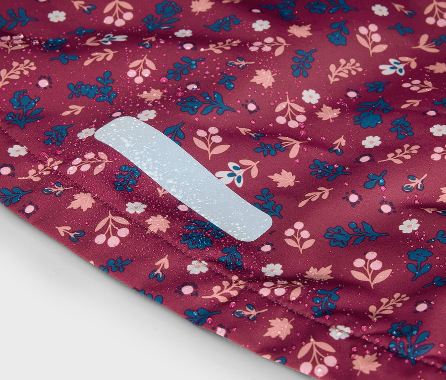 Nahaufnahme eines bordeauxroten Stoffes mit Blumenmuster und reflektierendem Streifen.
