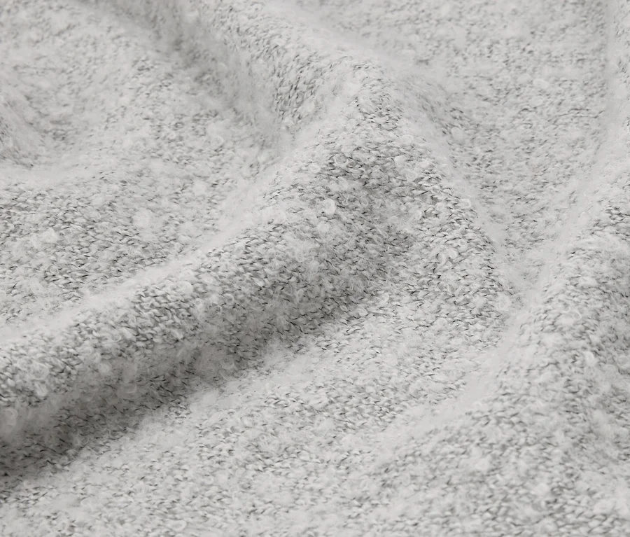 Nahaufnahme eines zerknitterten, hellgrauen Stoffes mit flauschiger Textur.