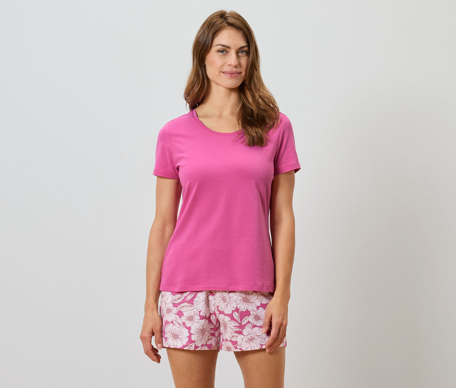 Frau trägt ein pinkes T-Shirt und Shorts mit Blumenmuster.