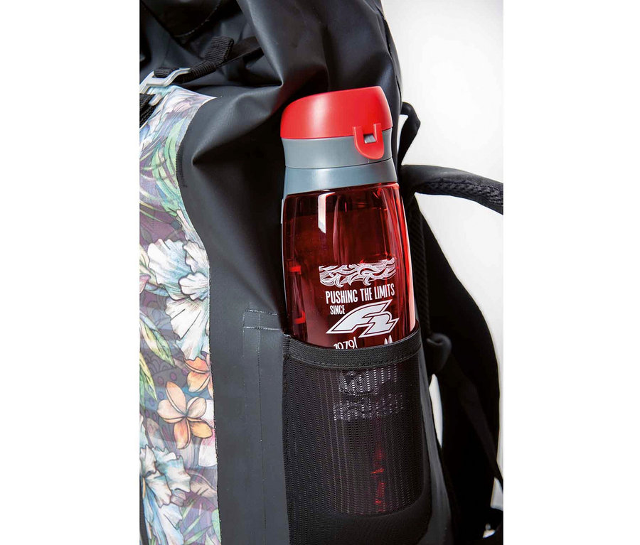 Eine rote Wasserflasche steckt in der Seitentasche eines Rucksacks mit Blumenmuster.