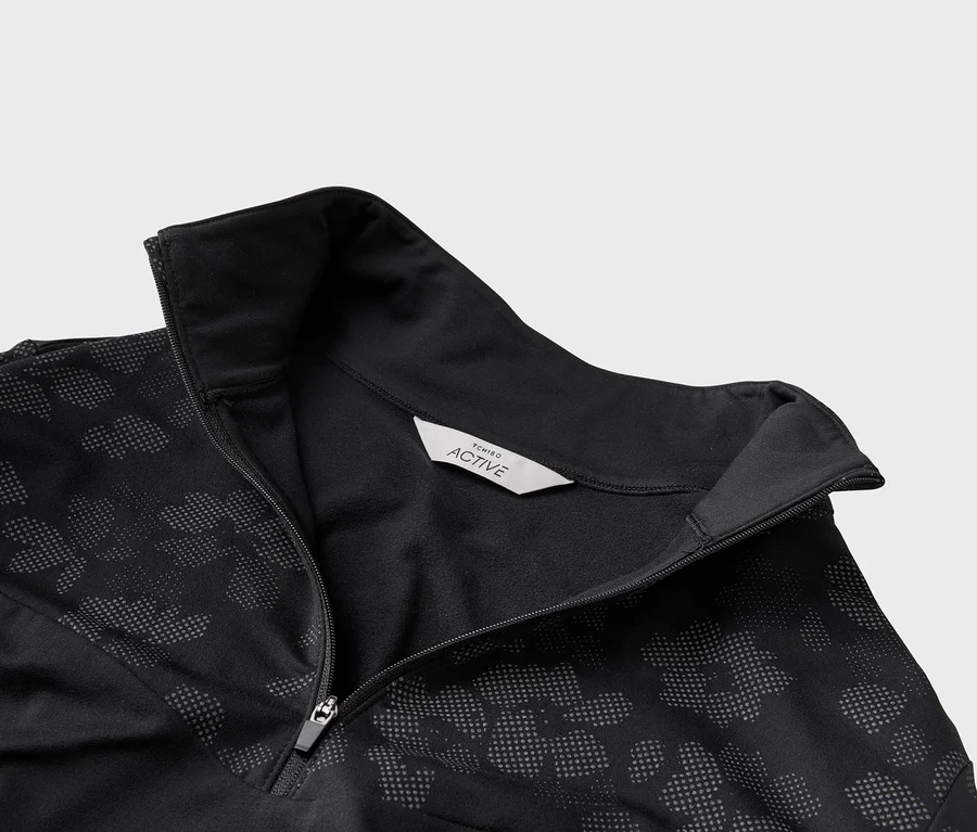 Nahaufnahme einer schwarzen Tchibo Active Jacke mit Reißverschluss und Punktmuster.