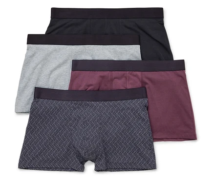 Vier Herren Boxershorts in Schwarz, Grau, Burgunderrot und mit Blattmuster liegen übereinander.