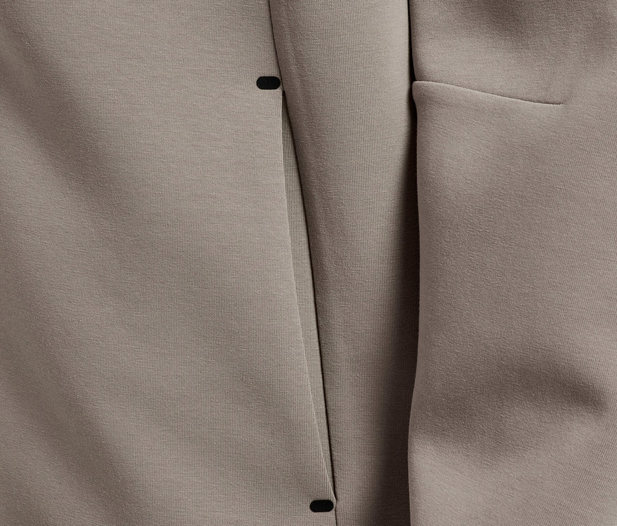 Detailaufnahme eines Kapuzenpullovers in Taupe mit minimalistischem Design und verdeckter Tasche.