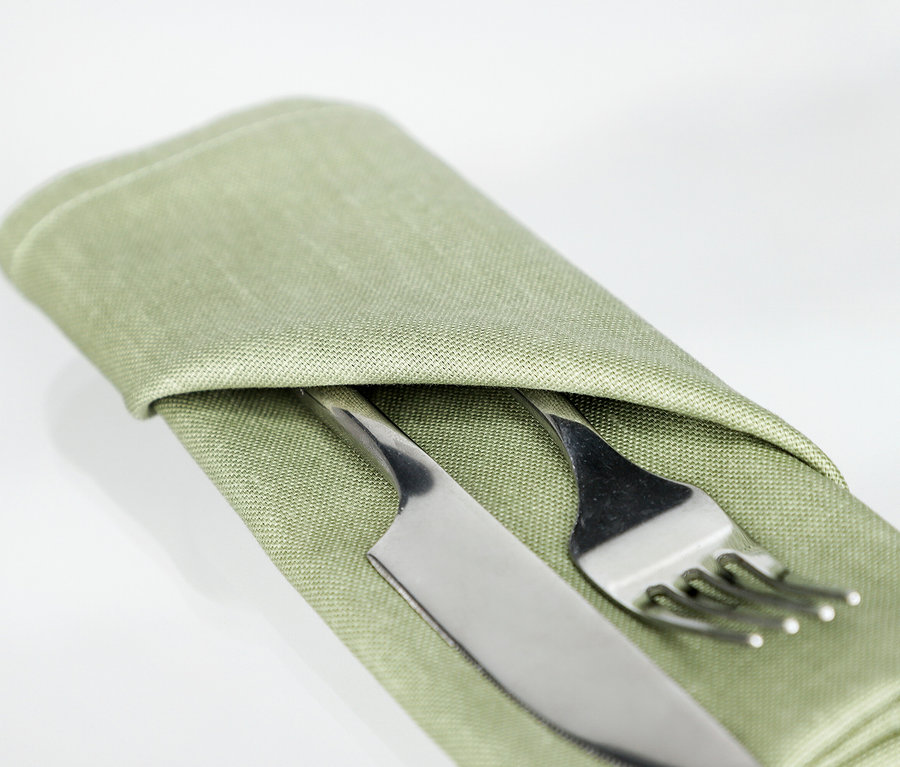 Eine khakifarbene SCHÖNER WOHNEN-Kollektion Serviette ist um ein Messer und eine Gabel gefaltet.