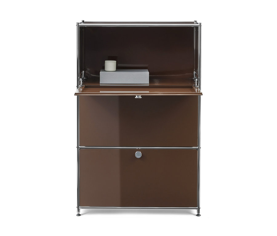 Brauner Schrank mit Chromrahmen, oben offen mit grauem Kasten und weißem Zylinder, darunter eine Klappe und eine Schublade mit Griff.