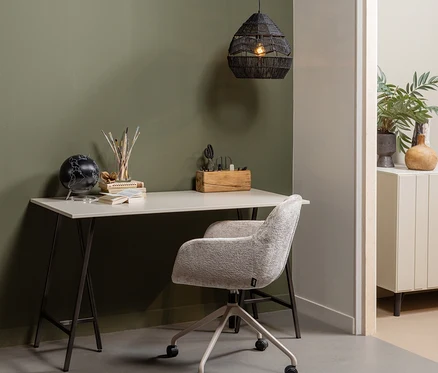 Ein Home-Office-Arbeitsplatz mit hellem Schreibtisch und hellgrauem Polsterbürostuhl. Auf dem Schreibtisch stehen ein schwarzer Globus, Künstlerbedarf und ein Holz-Organizer. Eine schwarze Hängeleuchte hängt darüber.