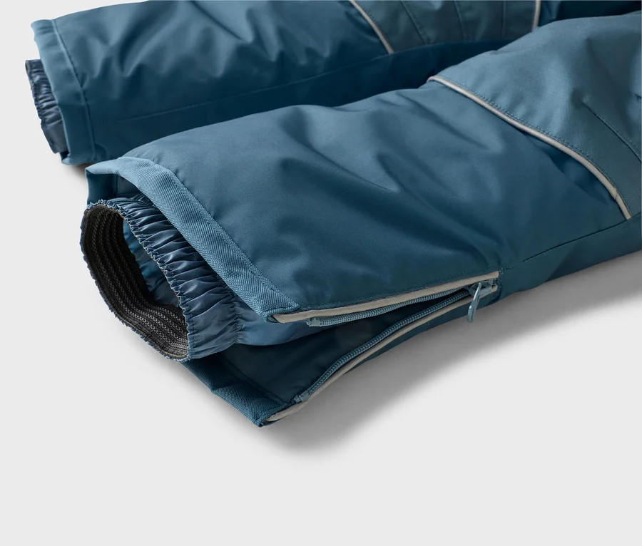 Nahaufnahme der Beinabschlüsse einer blauen Skihose mit elastischem Innenbündchen und seitlichem Reißverschluss.