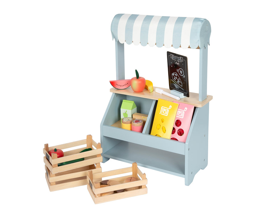 Ein hellblauer, kompakter small foot Kaufladen aus Holz mit blau-weiß gestreiftem Stoffdach. Auf der oberen Ablage liegen Spielzeug-Wassermelone, Apfel, Banane und eine Tafel. Die untere Ablage enthält Spielzeug-Milch, Behälter und 'fresh'-Boxen. Daneben stehen zwei Holzkisten mit Spielzeug-Obst, -Gemüse und -Brot.