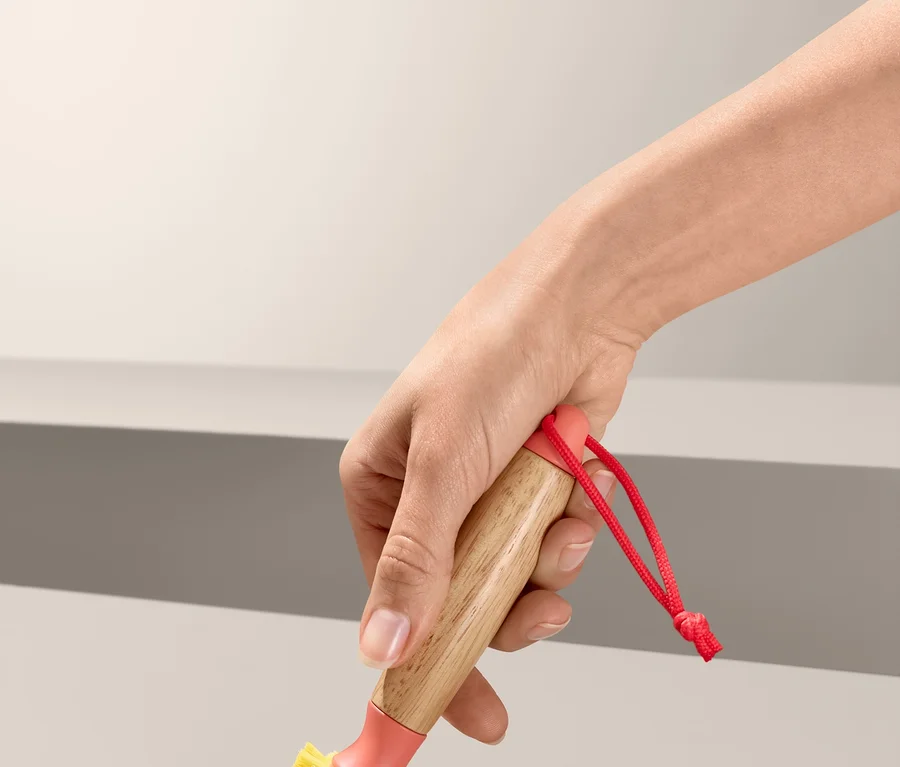 Eine Hand benutzt eine Universalreinigungsbürste an einem Abfluss.