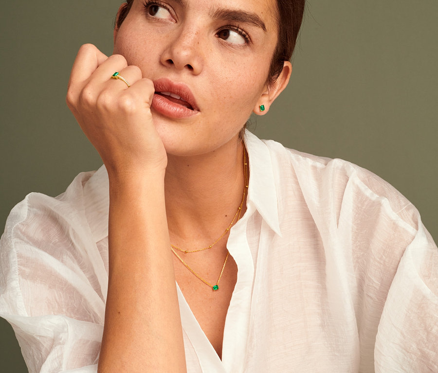 Frau trägt 585 Gold Ring mit grünem Zirkonia, 585 Gold Ohrstecker mit grünem Zirkonia und 585 Gold Kette mit grünem Zirkonia.