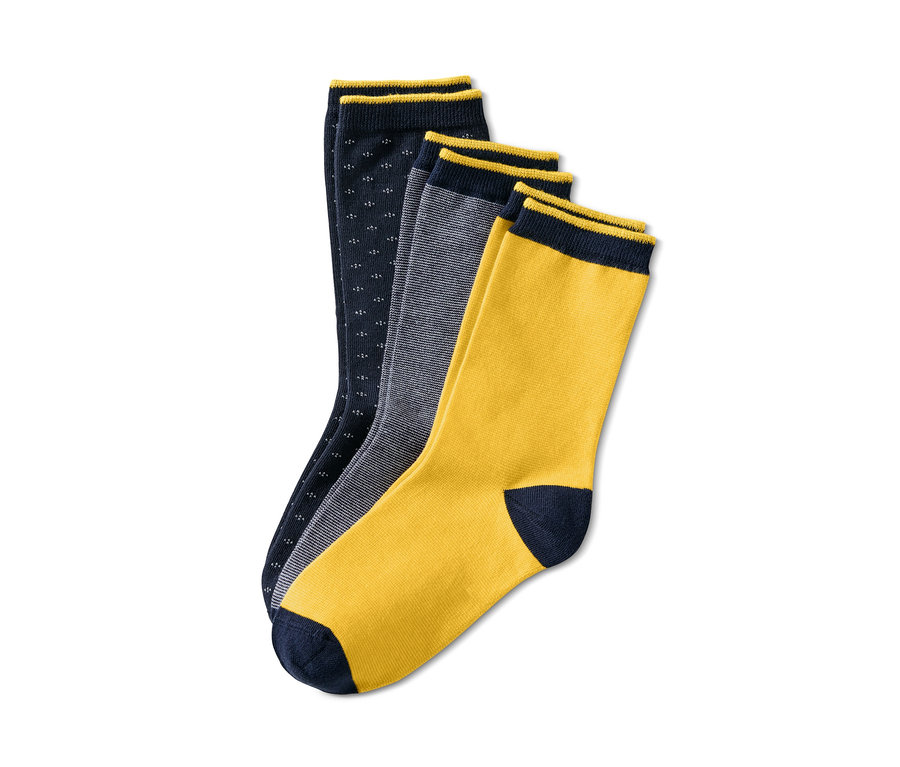 Drei Paar Socken liegen auf einem weißen Hintergrund. Ein Paar ist dunkelblau mit kleinen weißen Punkten, eines grau gestreift und eines gelb mit dunkelblauer Spitze. Alle Socken haben einen dunkelblauen Rand. 3 Paar Socken