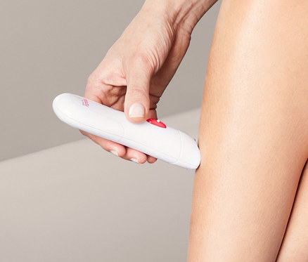 Frau epiliert ihr Bein mit einem Epilierer.