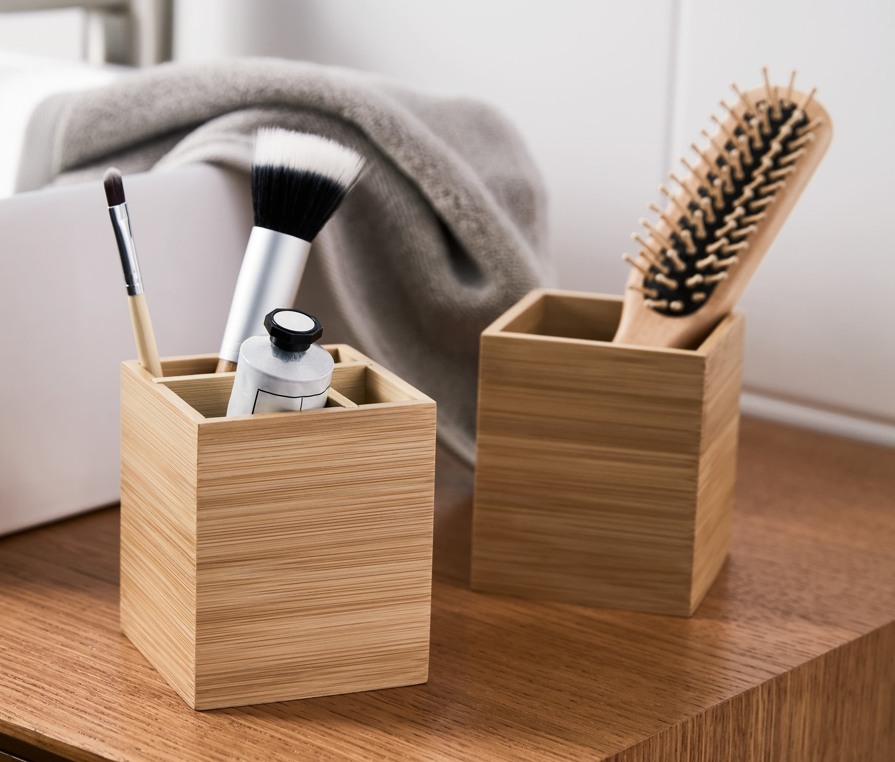 Zwei Bambus-Organizer stehen auf einem Waschtisch, einer mit Bürsten und Tube.