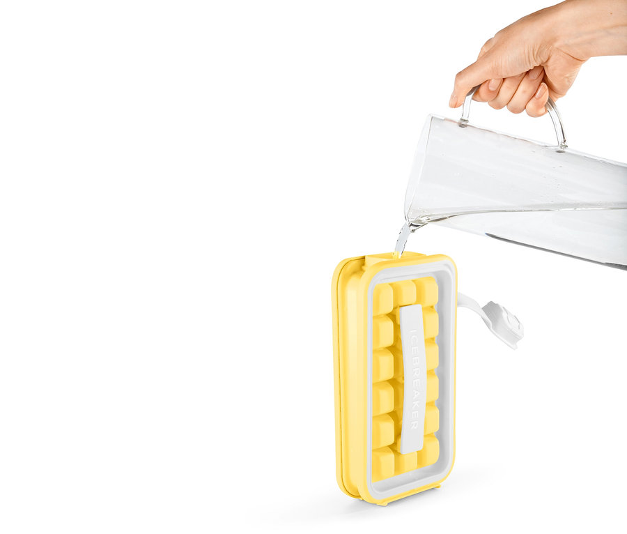 Eine Hand giesst Wasser aus einem Krug in den gelben Eiswürfelbereiter »ICEBREAKER® POP«.