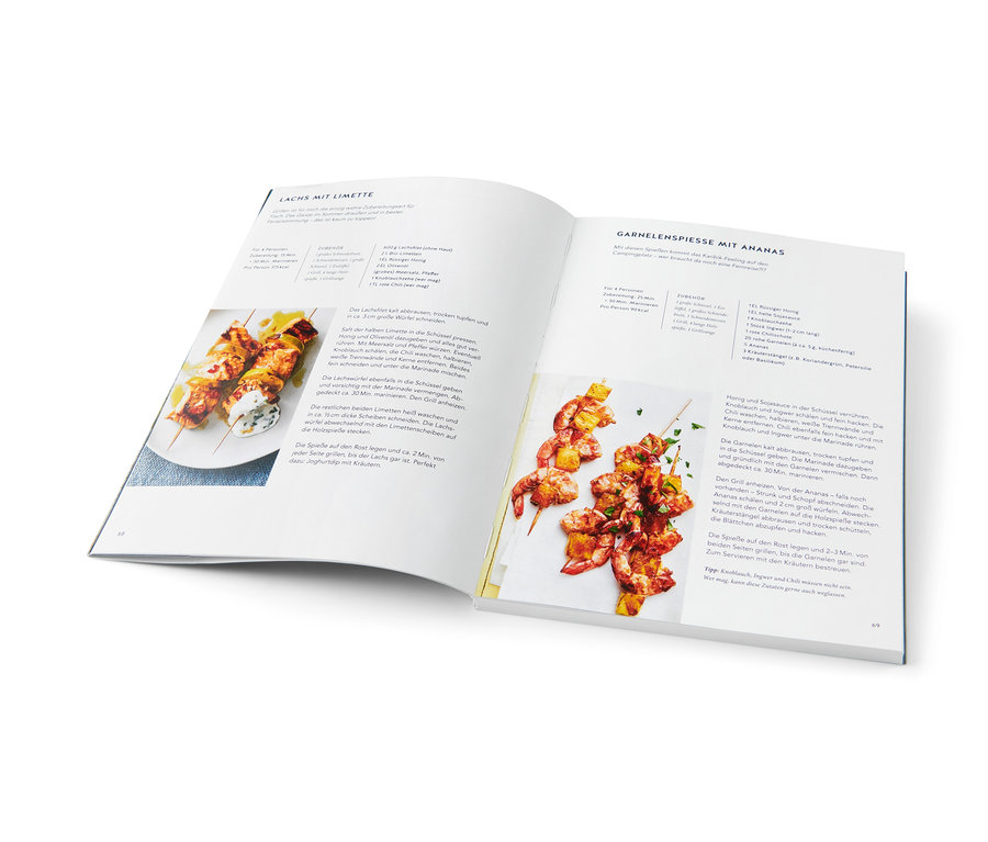 Kochbuch geöffnet auf einer Seite mit Rezepten für Lachs- und Garnelenspieße mit Ananas. Buch »Campingküche« sichtbar.