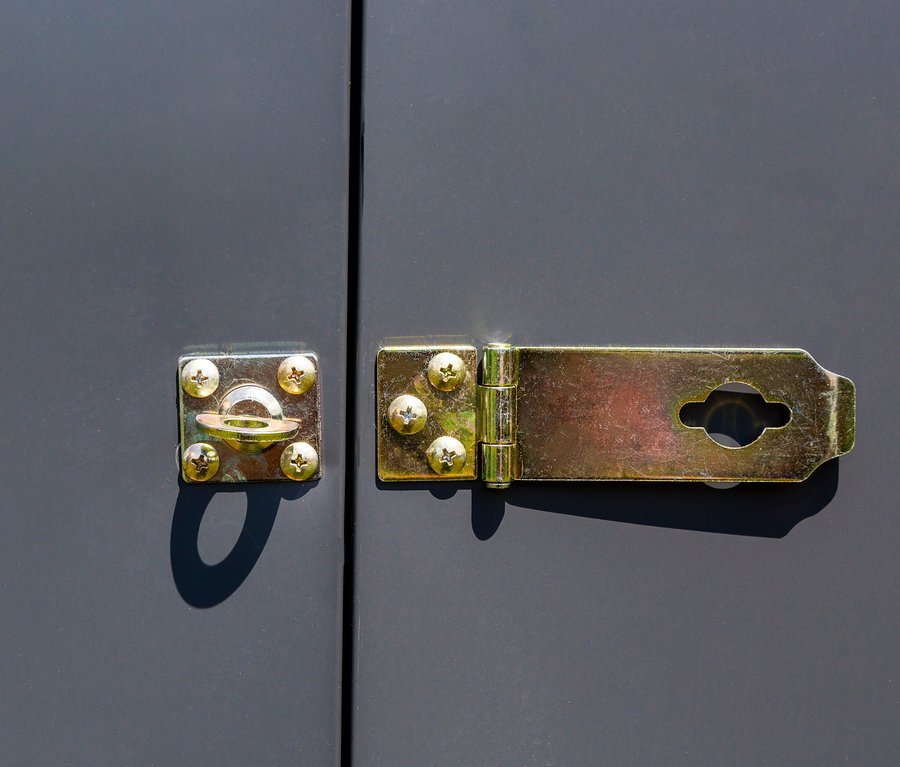 Detailaufnahme eines goldenen Schlosses an einer grauen Anlehnhaus Tür.