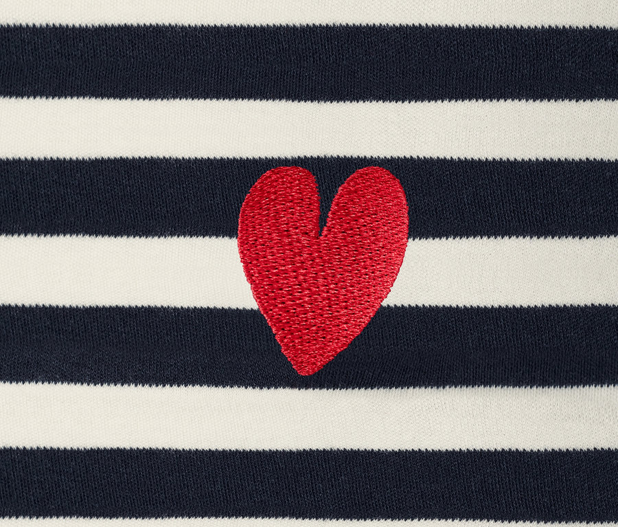 Detailansicht eines dunkelblau-weiß gestreiften Langarmshirts mit Stickerei eines roten Herzens.