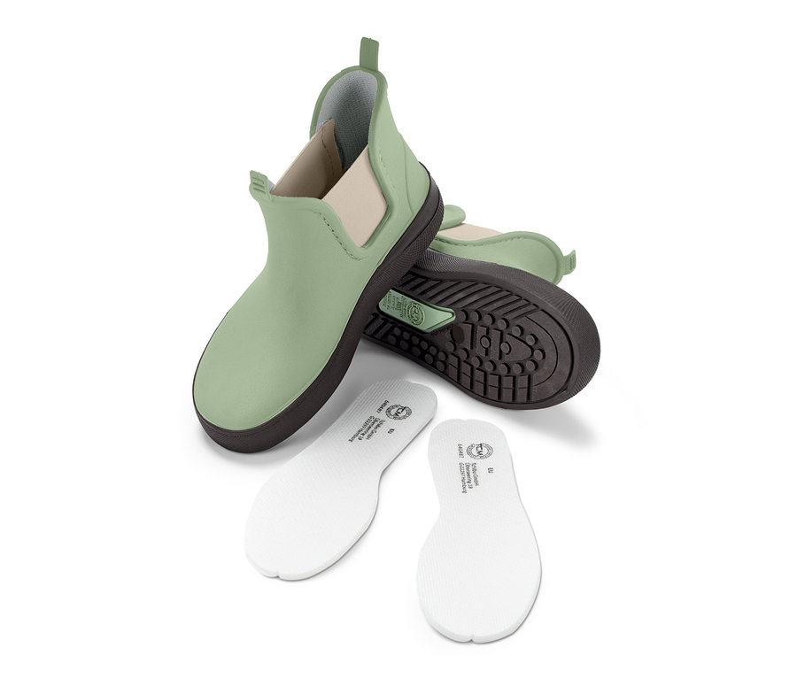 Grüne Chelseaboot-Gummistiefel und weiße Einlegesohlen auf weißem Hintergrund.