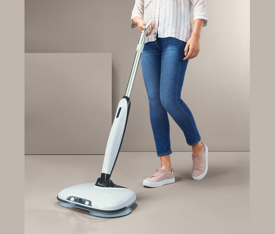 Frau benutzt elektrischen Bodenwischer.