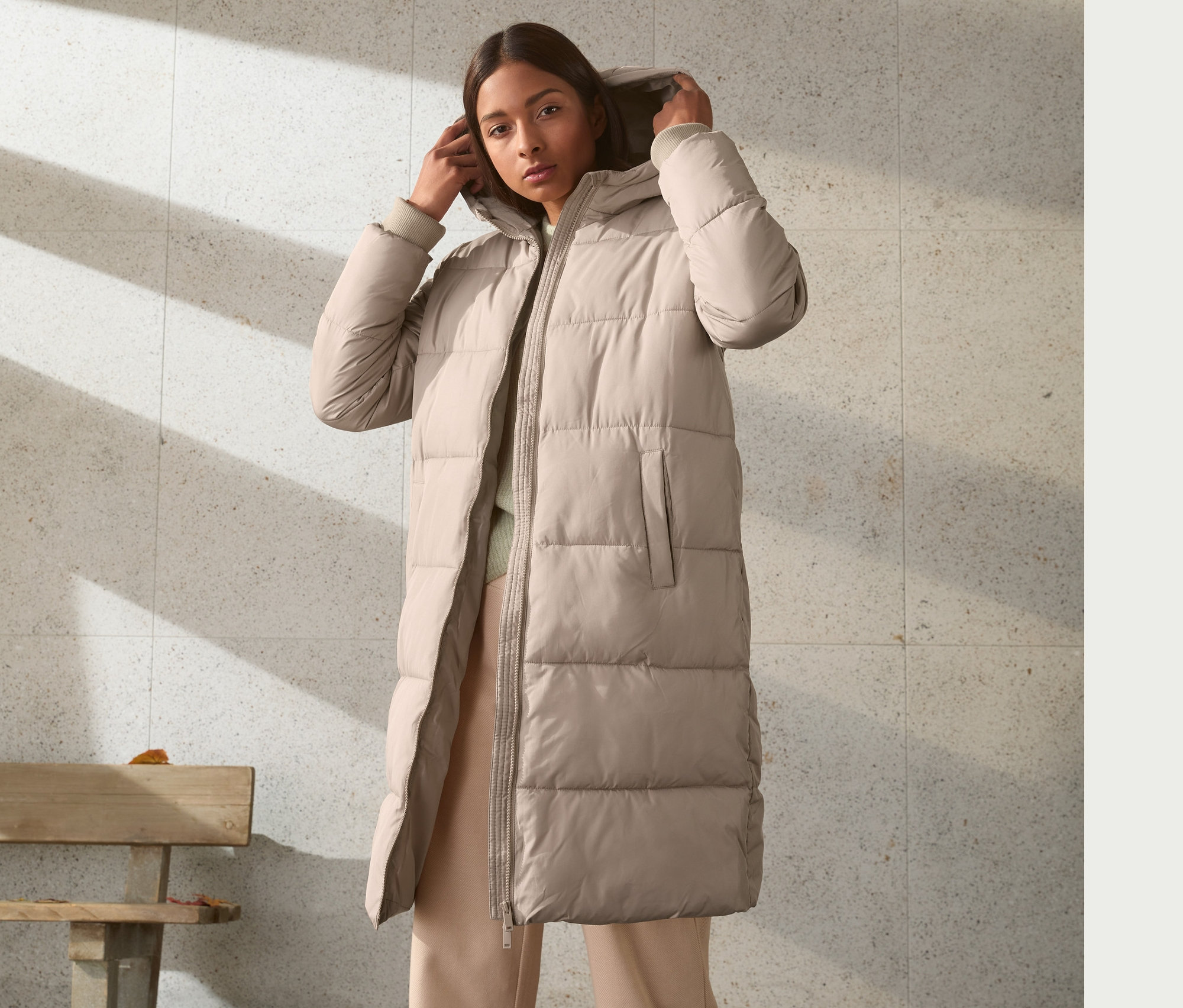 Frau richtet die Kapuze ihres Steppmantels.