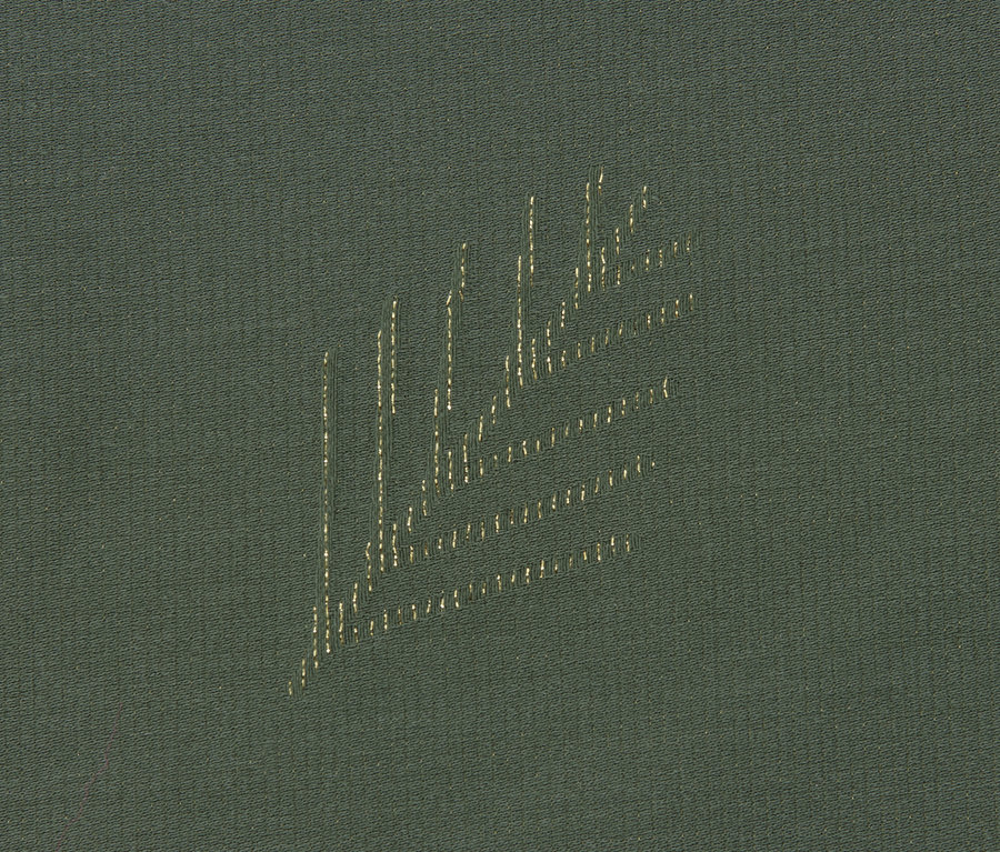 Detail einer grünen Jacquard-Tischdecke.
