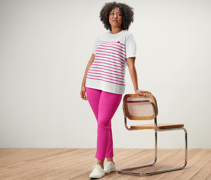 Frau posiert in einem gestreiften T-Shirt und einer pinkfarbenen Stretchhose.