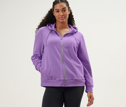 Frau posiert in Sporttight und lavendelfarbener Sweatjacke.