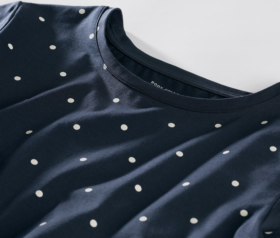 Detailaufnahme eines dunkelblauen Pyjamas mit weißen Punkten.
