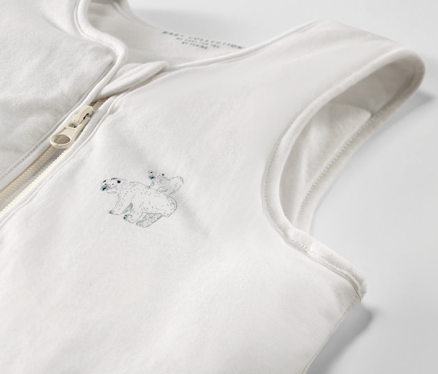 Detailansicht eines weißen Schlafsacks mit Beinen, verziert mit einem Eisbärenmotiv und einem Reißverschluss.
