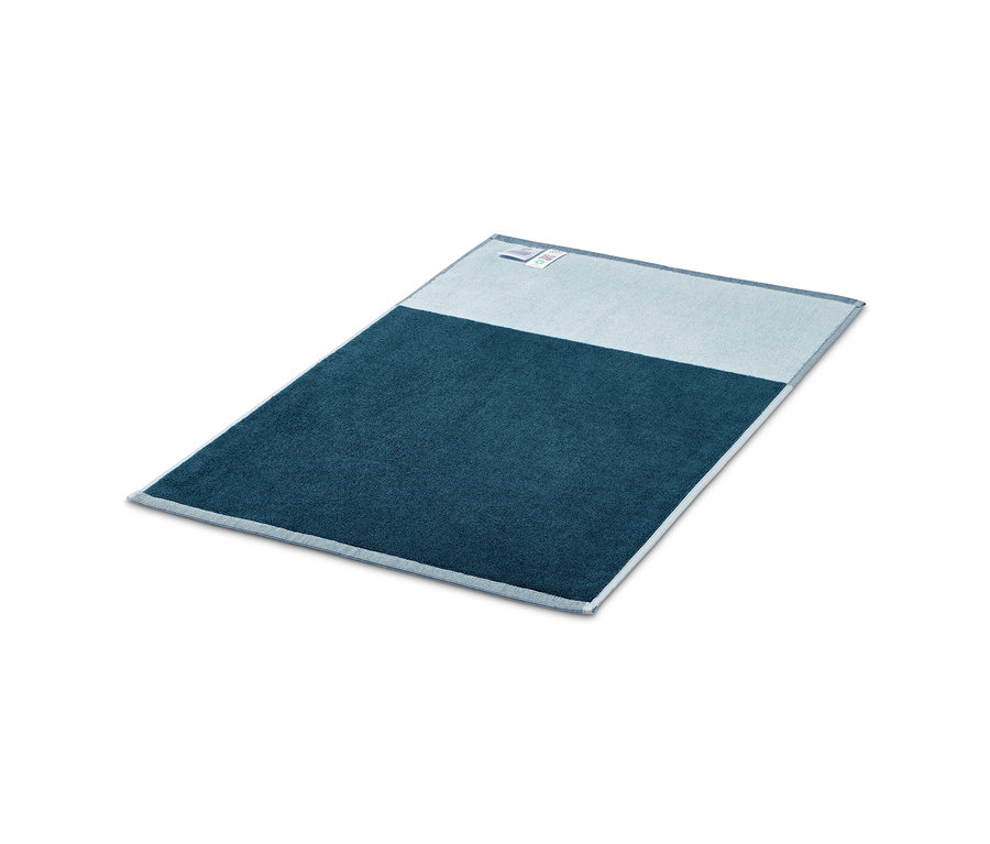 Ein blauer Jacquard-Duschvorleger liegt auf einem weißen Hintergrund.