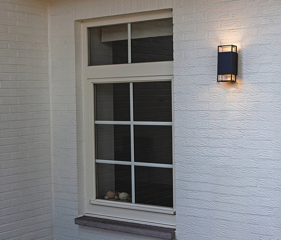 Weißes Backsteingebäude mit Fenster und Oudoor-Wandleuchte.