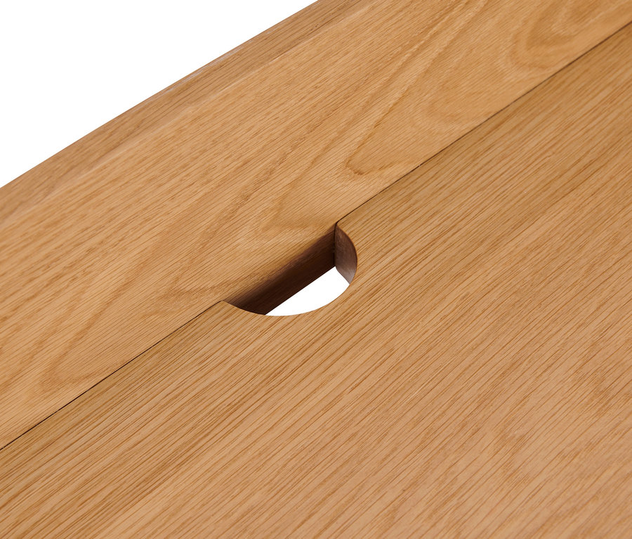 Detailaufnahme einer Schreibtischplatte aus Holz mit einer Aussparung für Kabel.