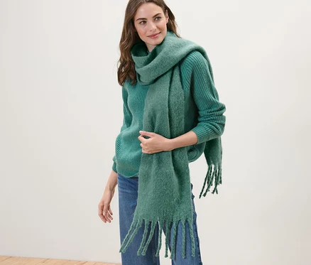 Frau trägt grünen Strickpullover und Webschal, grün.
