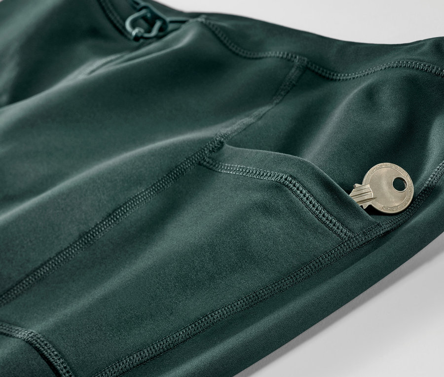 Detailaufnahme einer dunkelgrünen Thermo-Lauftight mit einem Schlüssel in der Tasche.