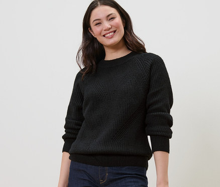 Lächelnde Frau trägt einen schwarzen Strickpullover.