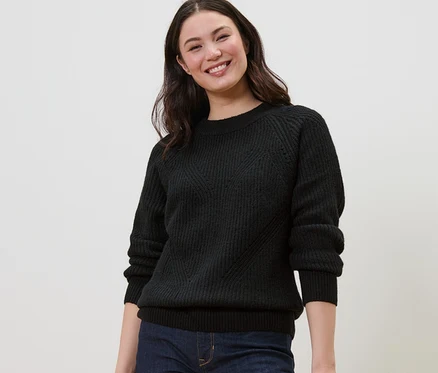 Lächelnde Frau trägt einen schwarzen Strickpullover.