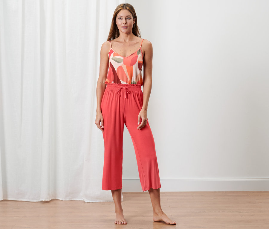 Frau posiert in korallefarbenem Pyjama in 7/8-Länge.