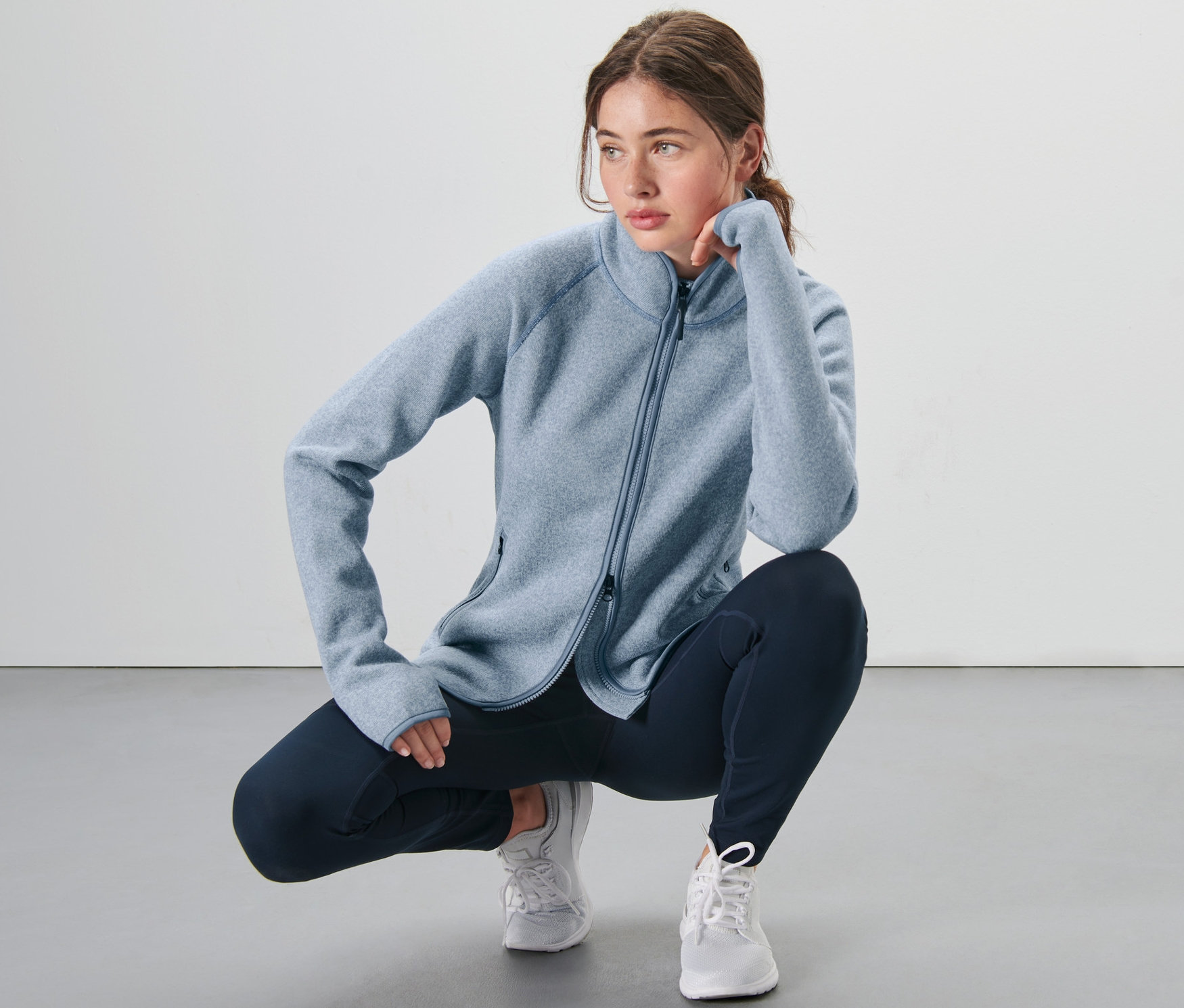 Frau hockt und trägt eine icegraue Strickfleece-Jacke.