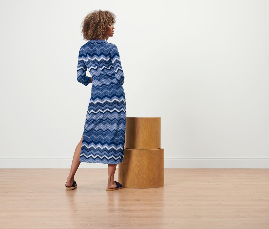 Frau steht mit dem Rücken zur Kamera und trägt ein Strickkleid.