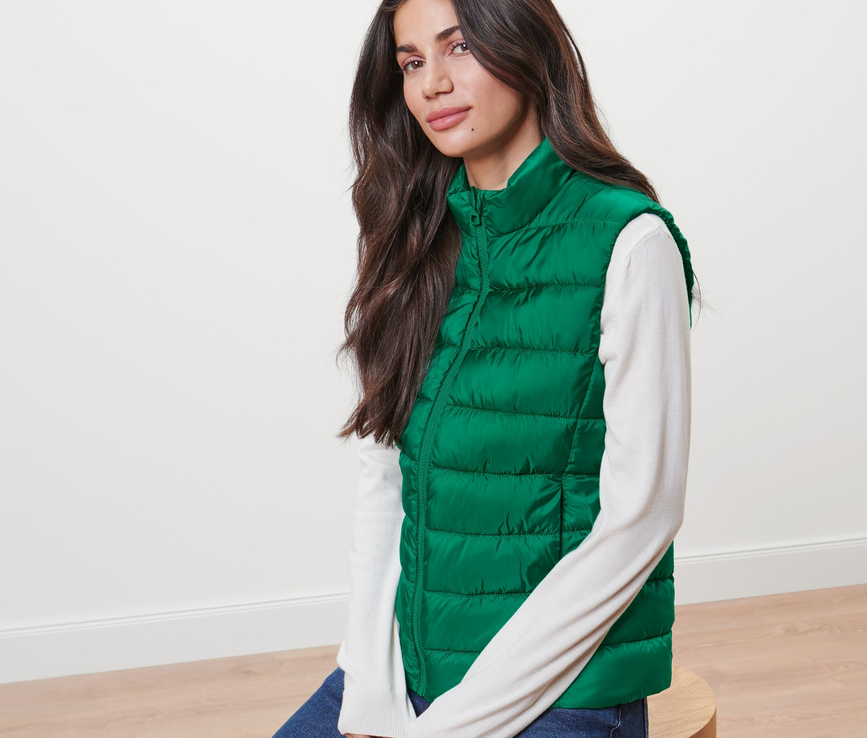 Frau sitzt und trägt eine grüne Steppweste.