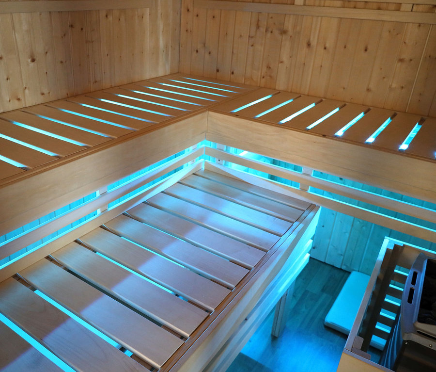 Innenansicht der Karibu Fasssauna "Nadi 1" mit Holzliegen und blauer Beleuchtung.