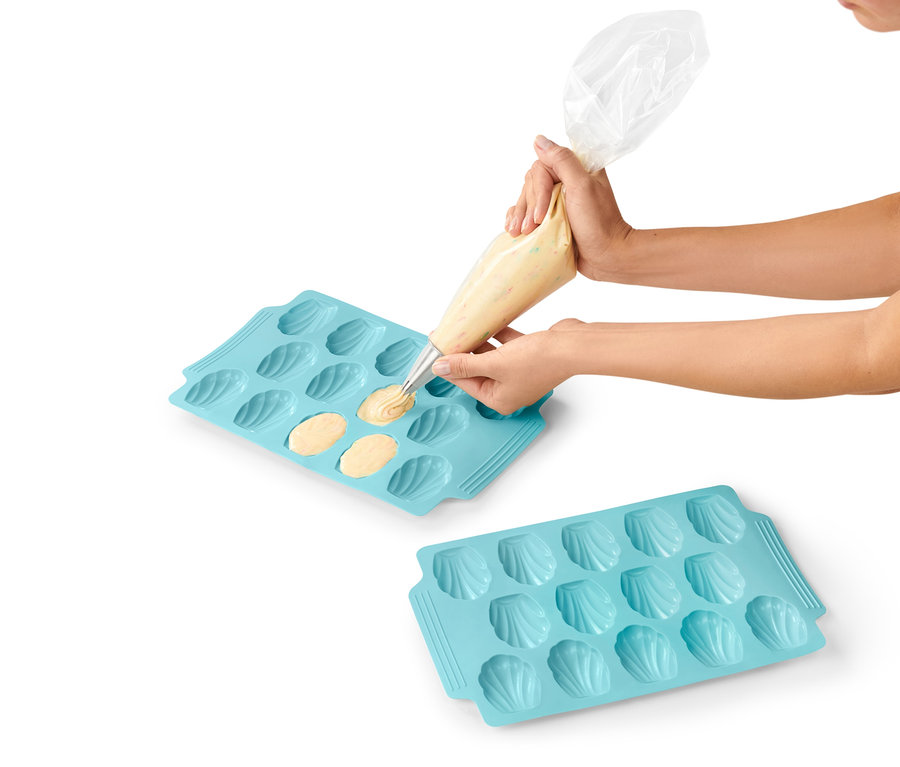 Frau füllt Teig in eine blaue 2 Madeleine-Backformen.